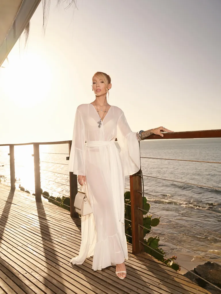 Kaftan branco no deck sobre o mar ao pôr do sol