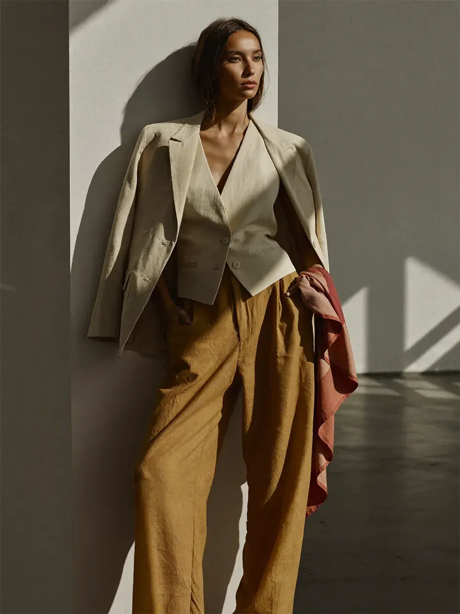 Editorial da marca Vetrina: modelo de blazer creme contra parede iluminada
